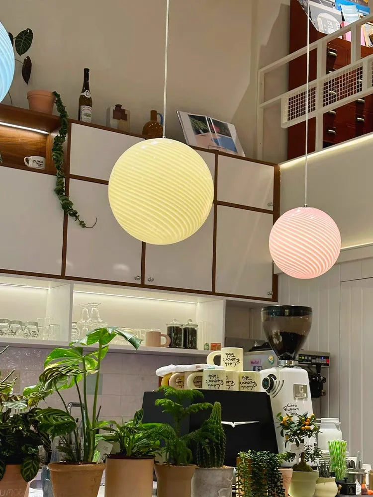 Murano style swirl glass globe pendant lamps in cream and pink, round handblown design, lit in interior setting